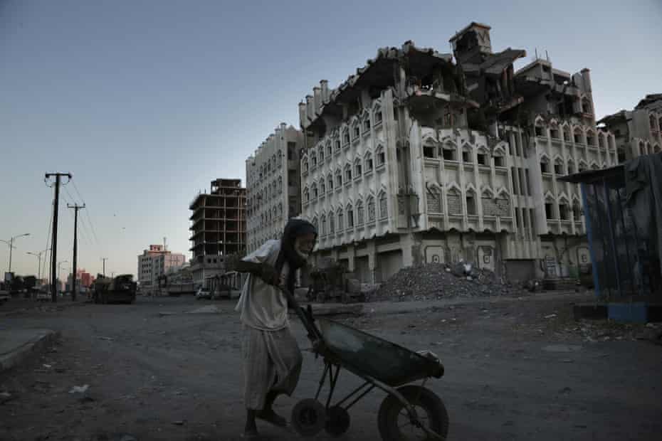An elderly man walks past a damaged building in Aden, Yemen, in 2018.