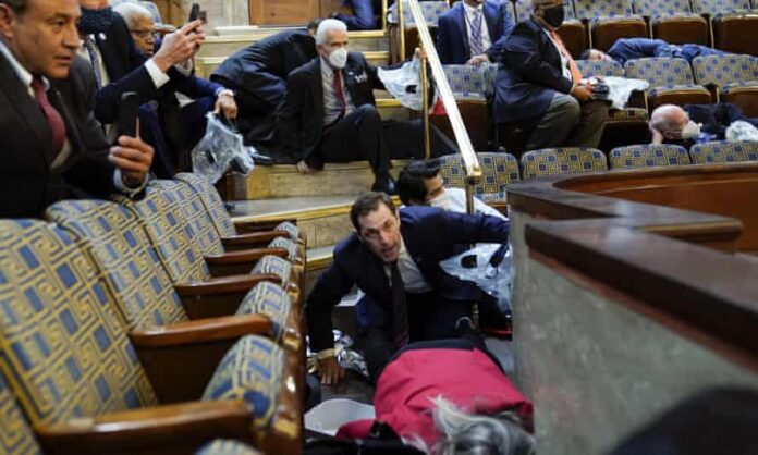 People shelter in the House gallery as rioters try to break into the House Chamber at the Capitol on 6 January. Trump’s impeachment trial will be held at the same place the violence unfolded.