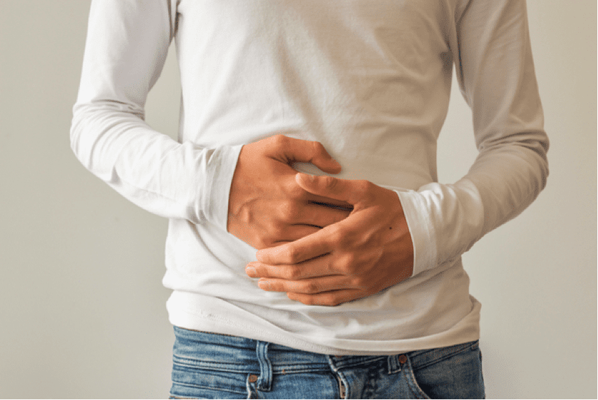 a man in a white shirt and jeans holding the front of his stomach with both hands