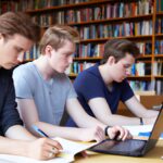 male college students studying in library with some laptops