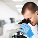 male scientist lookin in microscope