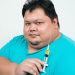 fat man and injection syringe beside him